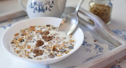 Bowl full of chocolate muesli with hearts and spoon, white and blue colors