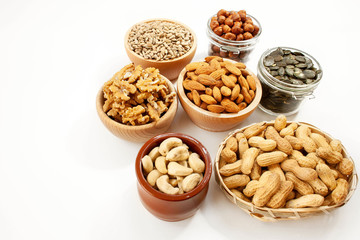 Containers filled with different types of nuts and seeds on a white background