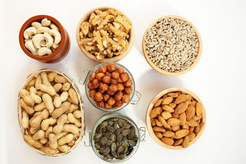 Containers filled with different types of nuts and seeds on a white background