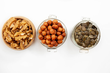Containers filled with different types of nuts and seeds on a white background
