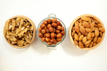 Containers filled with different types of nuts on a white background