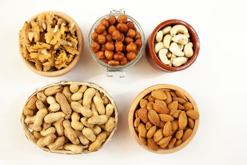 Containers filled with different types of nuts on a white background