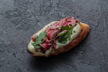 Bruschettas with roast beef on black background, copy space