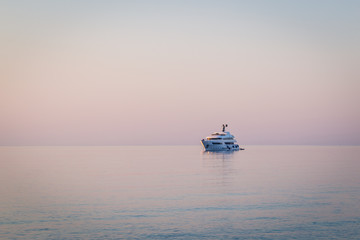 Luxury yacht on open sea at pink sunrise