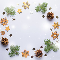 Christmas round frame with golden ornaments, painted snowflakes, pine cones, confetti on grey background, copy space
