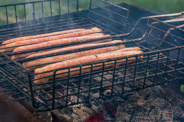 Grilled sausages. Cooking in the fresh air. The process of cooking meat. Concept: outdoor recreation, delicious, natural food, relaxation and entertainment.