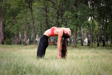 Young attractive smiling toned brunette woman stretching outside in a park. Healthy lifestyle concept