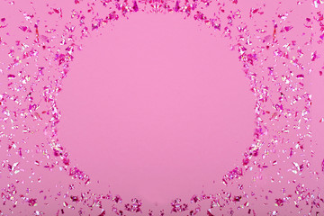 Obraz premium Pink confetti glitter sequins on pink background, top view