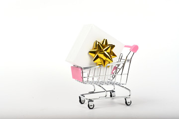 White gift box with bow in shopping cart isolated on white