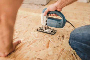 A carpenter works in a house with plywood and osb - inexpensive and quick decoration