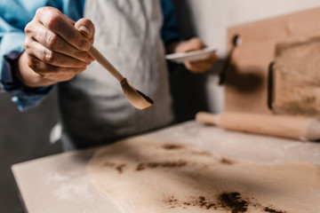 Closeup selective focus on a female hand that sprinkles cinnamon and spices while cooking