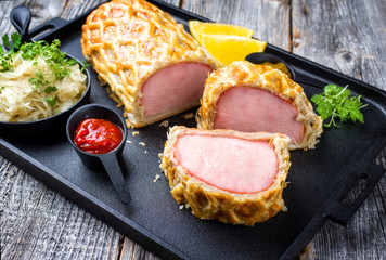 Gebackener Kasseler Schweinekamm Steak am Stück mit Sauerkraut und Ketchup angeboten als closeup...