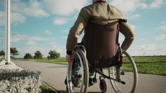 Outdoor walk of disabled man in wheelchair
