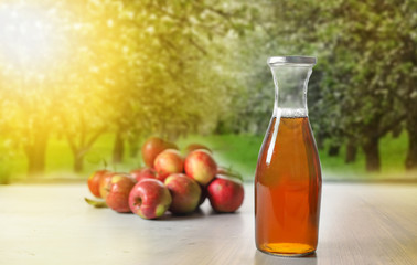 apple juice in glass bottle  and apples on Woden Provence table on natural background 