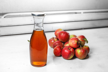 apple juice in glass and bottle and apples on Woden Provence table