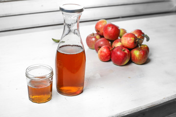 apple juice in glass and bottle and apples on Woden Provence table
