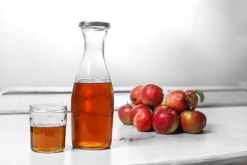apple juice in glass and bottle and apples on Woden Provence table