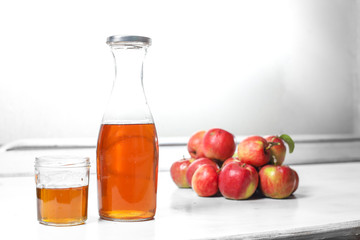 apple juice in glass and bottle and apples on Woden Provence table