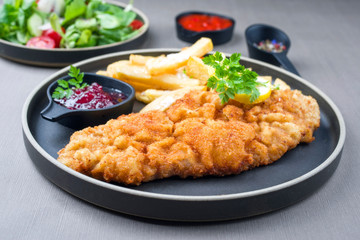 Frittiertes Wiener Schnitzel vom Kalb von der Oberschale mit Pommes Frites und Salat als closeup...