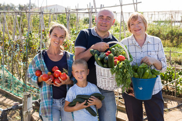Cheerful family with harvest of vegetables on the plantation