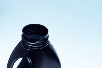 The neck of a black bottle with detergent on blue background