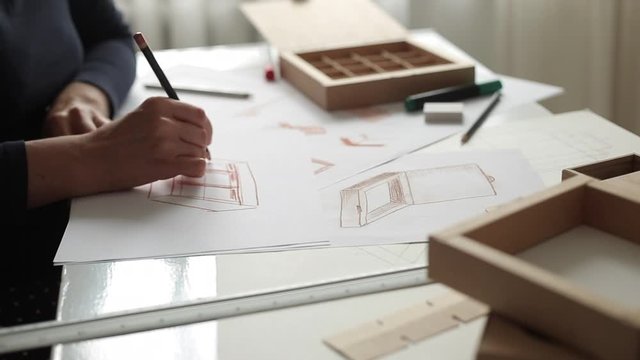 Designer draws a mockup for crafting cardboard box. Development of packaging design sketch.