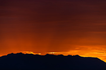Sunrise dawn with dark silhouette of mountains and red sunlight on Great Salt Lake in Antelope Island State Park from Ladyfinger campground in Utah