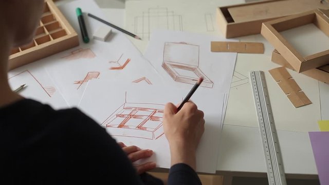 Designer draws a mockup for crafting cardboard box. Development of packaging design sketch.