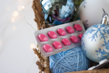 pharmacy theme. pink pills in a basket with christmas balls in blue on a white background with lights