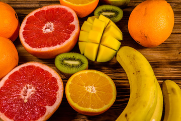 Still life with exotic fruits. Bananas, mango, oranges, grapefruit and kiwi fruits on wooden table