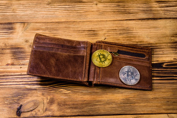 Brown leather wallet and bitcoins on the wooden background