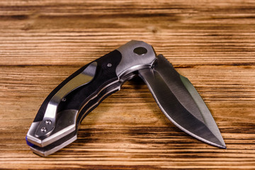 Opened folding knife on a wooden table