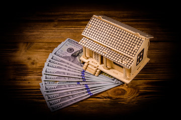 Plywood model of the house and one hundred dollar banknotes. Loan, real estate concept