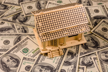 Plywood model of the house and one hundred dollar banknotes. Loan, real estate concept