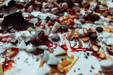Mixed sweets, chocolates and fruits on white table.