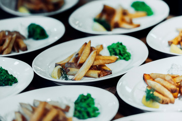 French fries on multiple white plates with dark background.