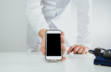 The doctor holds a phone with a blank display. Medical and pharmaceutical concept. The concept of showing medical information on the screen of a mobile phone.