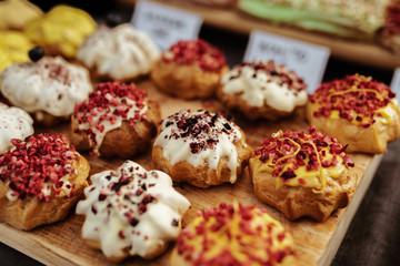 Colourful small cakes placed on a wood plank.