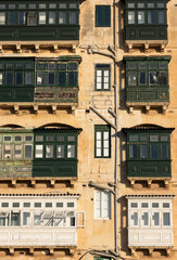 White and green balconies in tenement house in Valletta, Malta