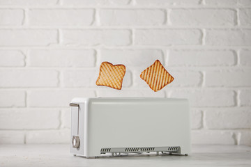 Roasted toast bread popping up of toaster with white brickwall