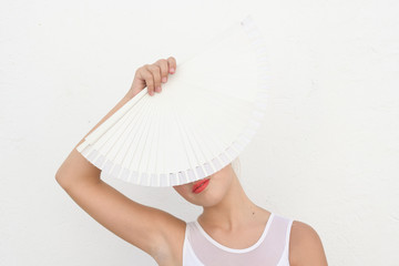 Flamenco dancer with her face covered with a white fan showing only the lips on a white background