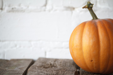 Close-up autumn pumpkin on thanksgiving table, white brick backdrop, selective focus