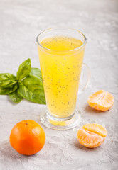 Glass of tangerine orange colored drink with basil seeds on a gray concrete background. Side view
