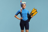 Woman in a snorkeling suit holding fins and wearing a diving mask
