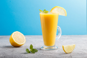 Glass of lemon drink on a gray and blue background. Side view