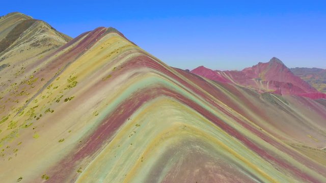 Aerial landscape of hiking scene at Rainbow Mountain at  Vinicunca Valley. Apu Ausangate is behind. All rocks, mountains and sand is invaded by red colors. Cusco Region, Peru