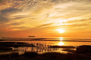 Naklejka na ściany i meble romantischer Abendhimmel an der Nordseeküste bei Cuxhaven, Sonnenuntergang im Wattenmeer mit Schiff