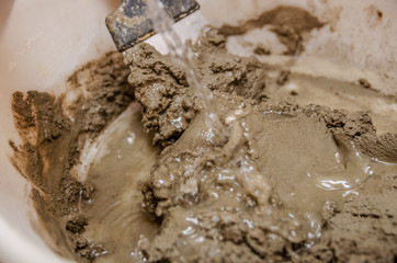 Fototapeta na wymiar Mixing cement with water closeup. Mixing of cement and water with a spatula