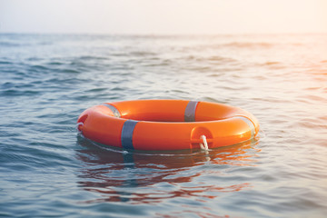 Orange lifebuoy in sea on water. Life ring floating on top of water. Life ring in ocean.Toning. - obrazy, fototapety, plakaty