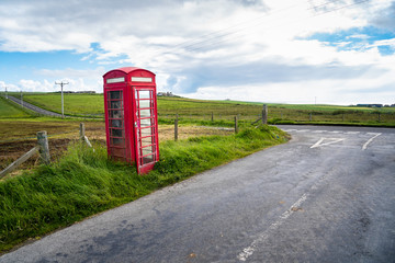 Lonely traditional Bristish telephone booth near an intersection between two back roads on a partly...
